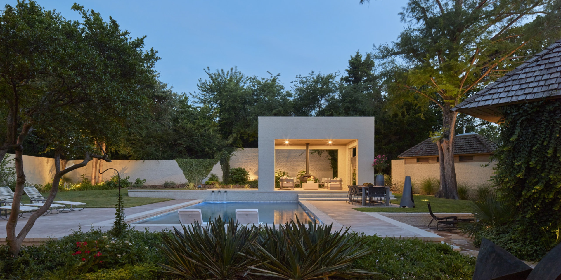 Modern pool pavilion with covered outdoor living space at dusk
