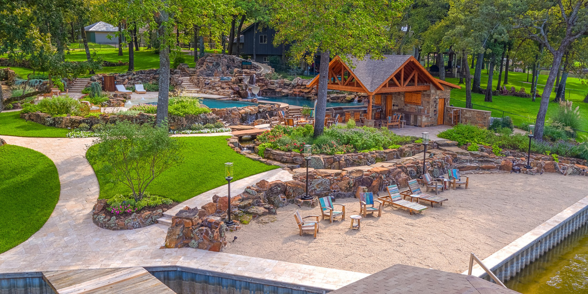 Lakefront resort-style pool with rock waterfalls and pavilion