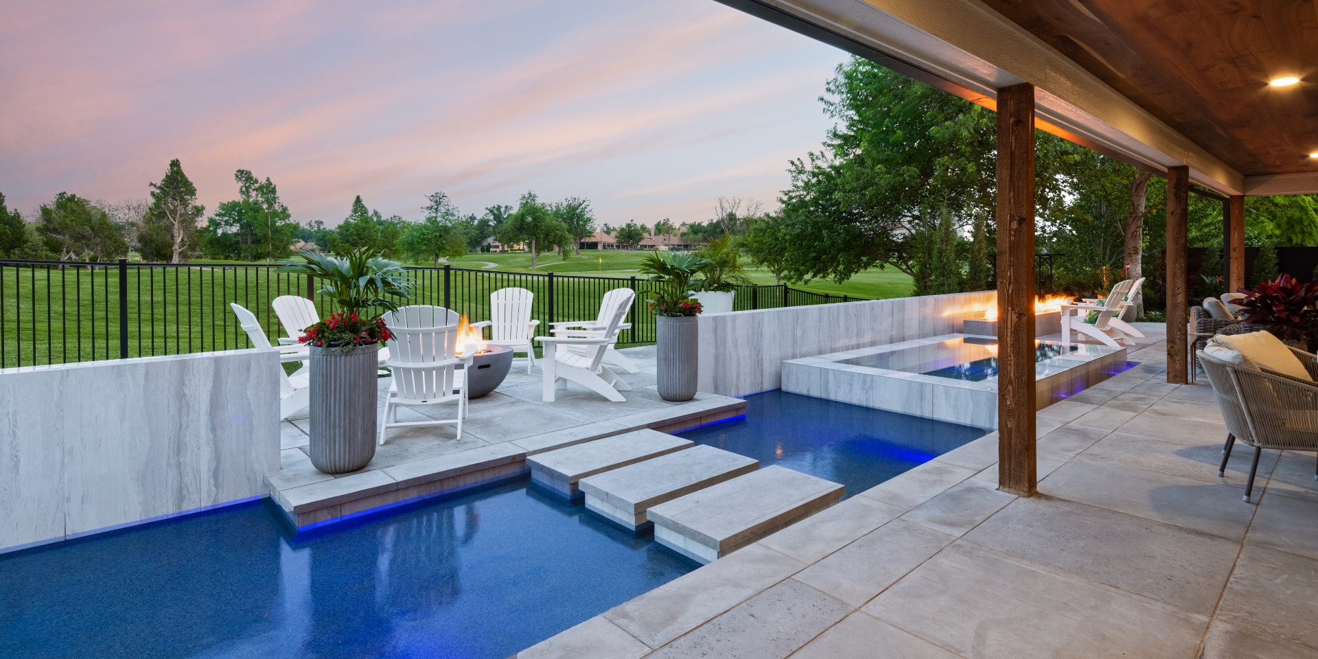 Poolside fire pit and spa at dusk overlooking a golf course