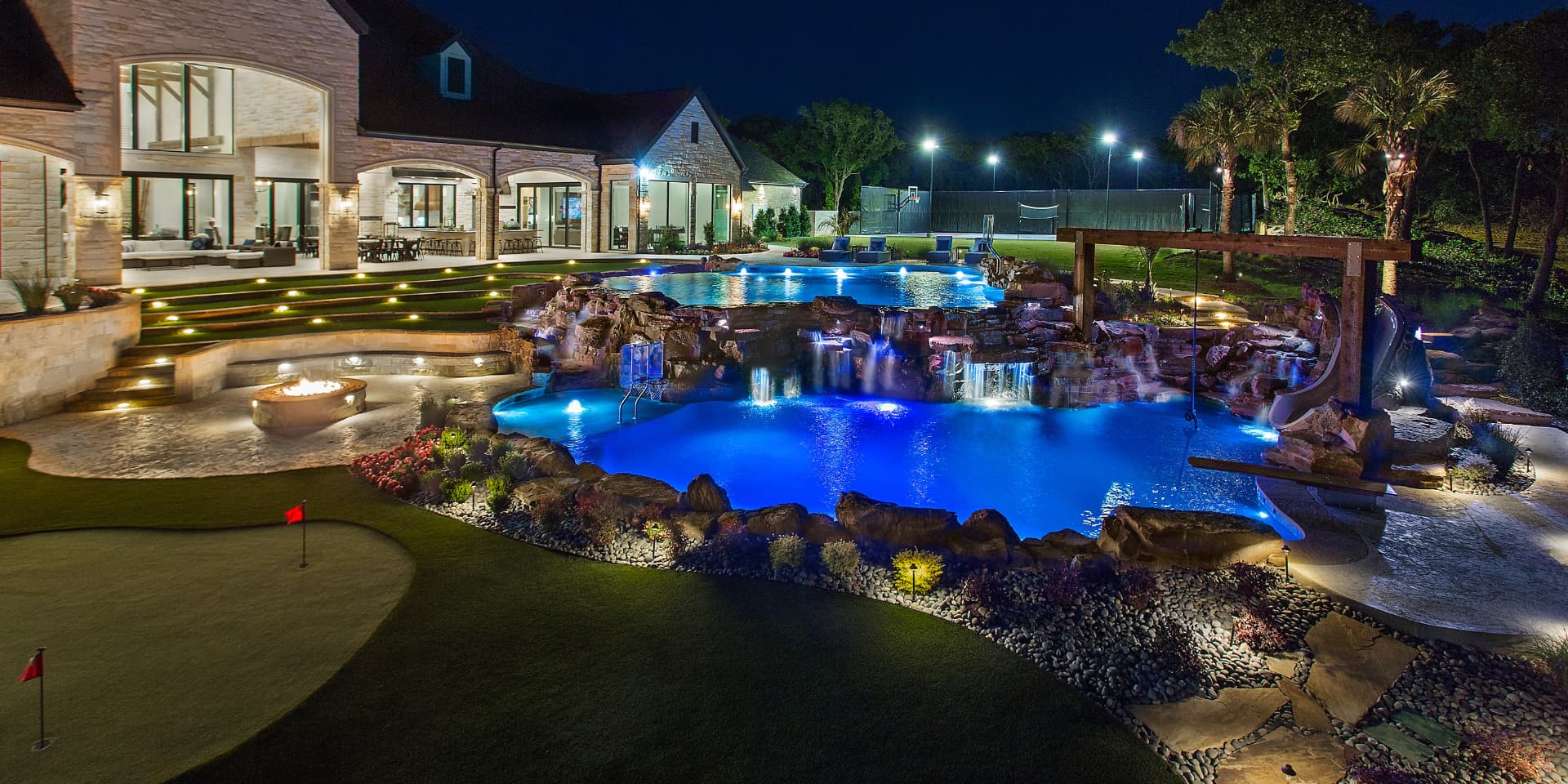 Night view of a grotto pool with waterfalls and putting green