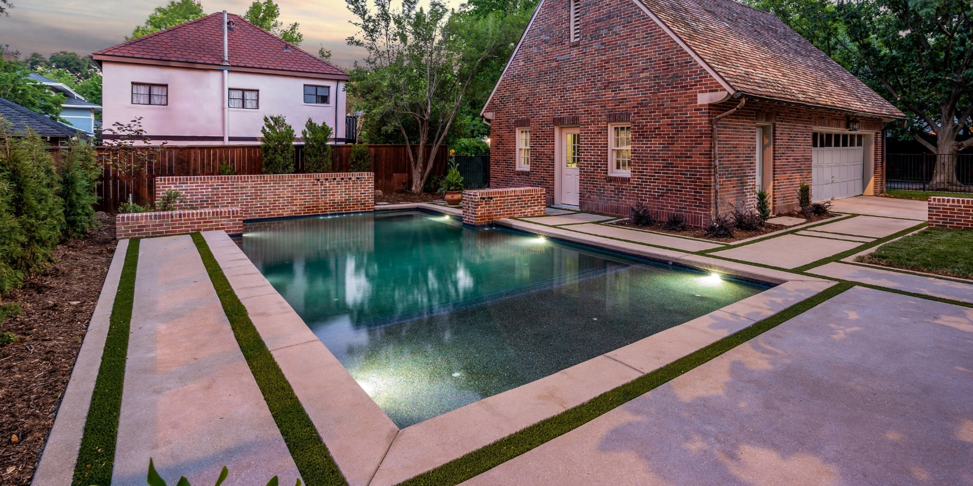 Rectangular pool with brick wall scuppers behind a Tudor home
